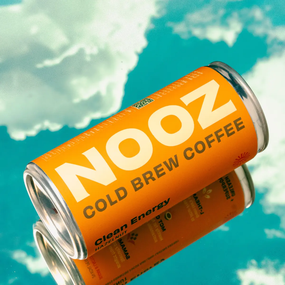 Two NOOZ cold-brew coffee cans floating against a turquoise sky