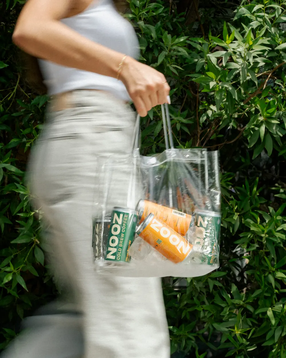A shopper carrying NOOZ cans in a clear reusable tote